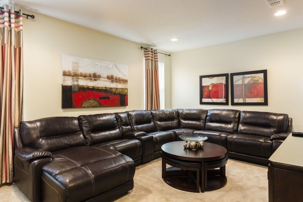 A living room with a sectional sofa, a round coffee table, and two framed artworks on the wall.