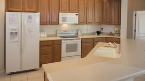 A kitchen with wooden cabinets, a white refrigerator, a microwave, a stove, and a sink. - Ip60121 - Highlands Reserve - 4 Bed 2 Baths Villa (Davenport)