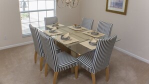 A dining area with a glass table, striped chairs, a chandelier, and a framed picture on the wall. - Ip60121 - Highlands Reserve - 4 Bed 2 Baths Villa (Davenport)