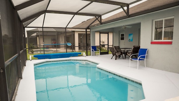 A swimming pool with a glass enclosure, surrounded by outdoor seating and a covered patio area. - Ip60285 - Hillcrest Estate - 4 Bed 3 Baths Villa (Davenport)