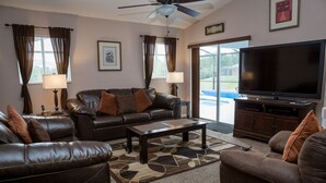 A living room with a leather couch, a coffee table, a flat-screen TV, and a ceiling fan. - Ip60285 - Hillcrest Estate - 4 Bed 3 Baths Villa (Davenport)