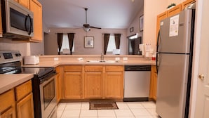 A compact kitchen with wooden cabinets, a microwave, a stove, a dishwasher, and a refrigerator. - Ip60285 - Hillcrest Estate - 4 Bed 3 Baths Villa (Davenport)