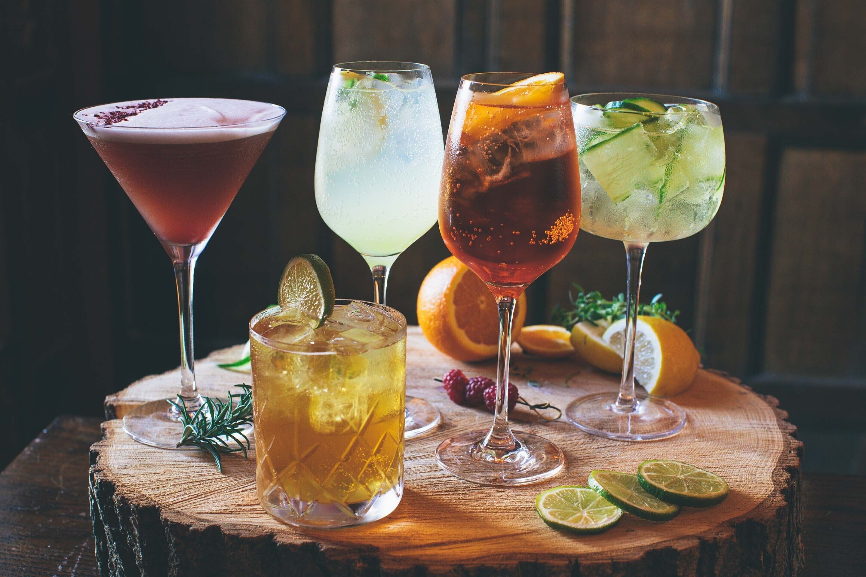 Four different cocktails on a wooden table with a rustic background.