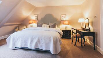 A bedroom with a large bed, two bedside tables with lamps, a wooden chair, and a desk with a mirror.
