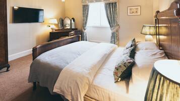Une chambre d’hôtel avec un lit, une télévision, un bureau avec une lampe et une fenêtre avec des rideaux.