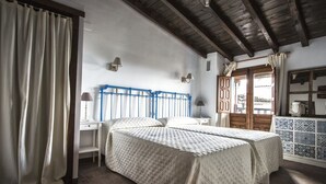 A bedroom with two beds, a wooden ceiling, and a view of the outside. - El Tomillar CR (Pasaron de la Vera)