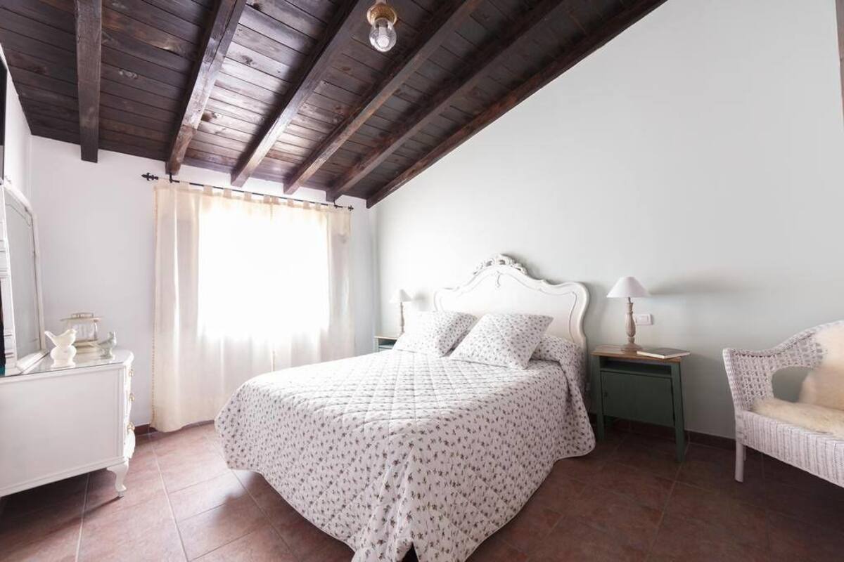A bedroom with a bed, a nightstand, a chair, and a dresser.