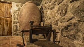 A stone-walled room with a large clay pot and a wooden bench. - El Tomillar CR (Pasaron de la Vera)