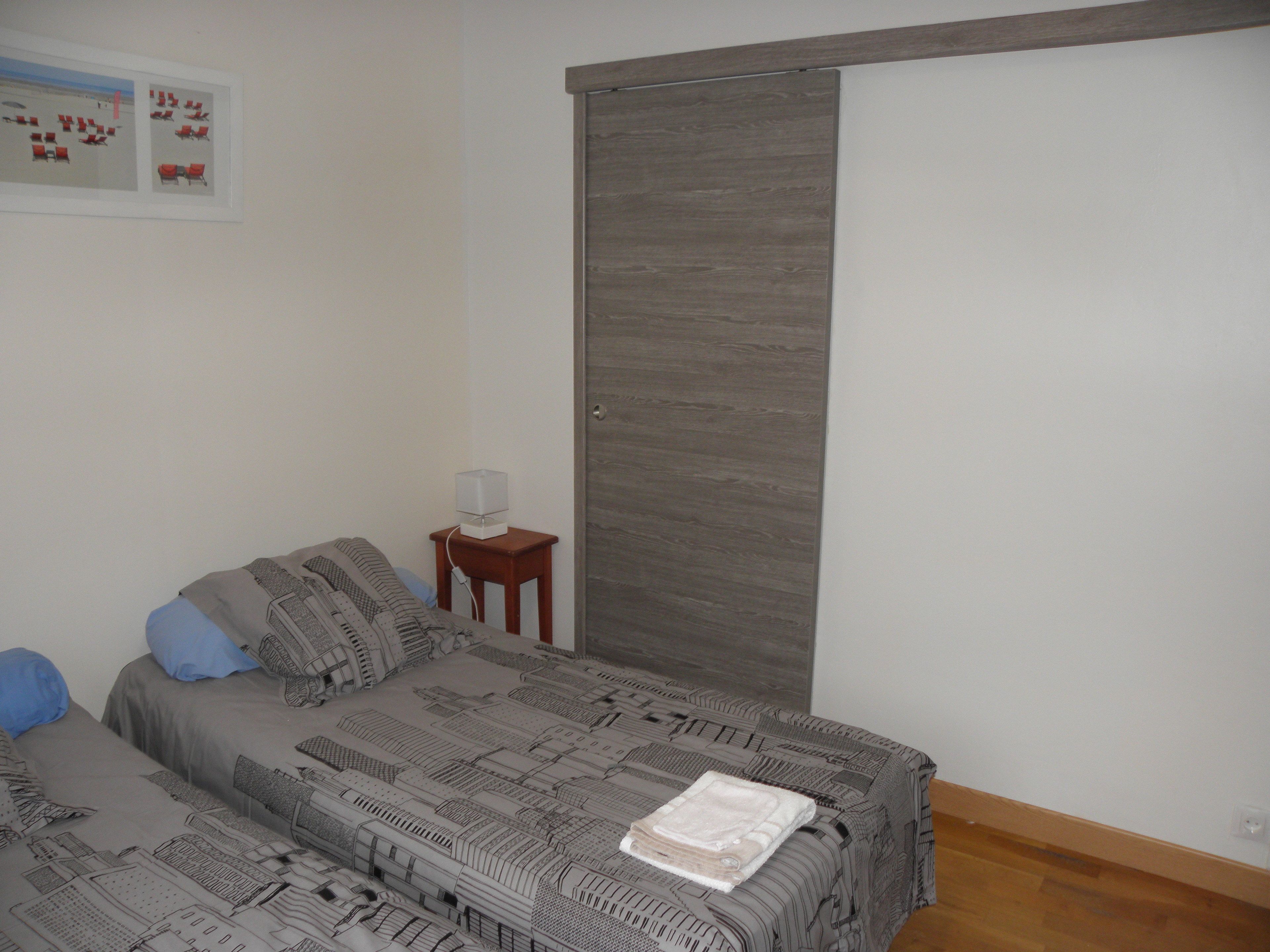 A bedroom with a bed, a nightstand, a lamp, and a wardrobe.