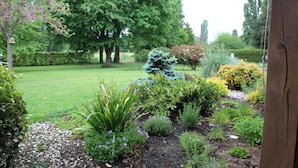 A garden with various plants and trees, a gravel path, and a wooden fence. - Chambres d'hôtes La Planche Pinçon (Teloché)