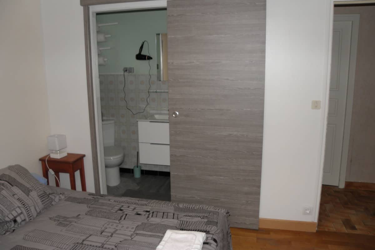 A bedroom with a bed, a bedside table, and a wardrobe with a mirror.