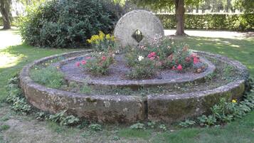 A circular stone structure with a central hole, surrounded by a ring of flowers and greenery.