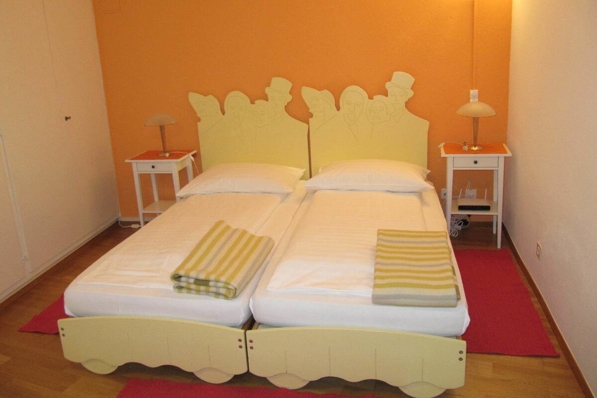 Una cama doble con cabecera, dos mesitas de noche y una alfombra roja en el suelo.