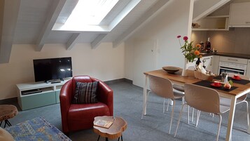 Una sala de estar acogedora con un sillón de cuero rojo, una mesa de comedor de madera y un televisor de pantalla plana.