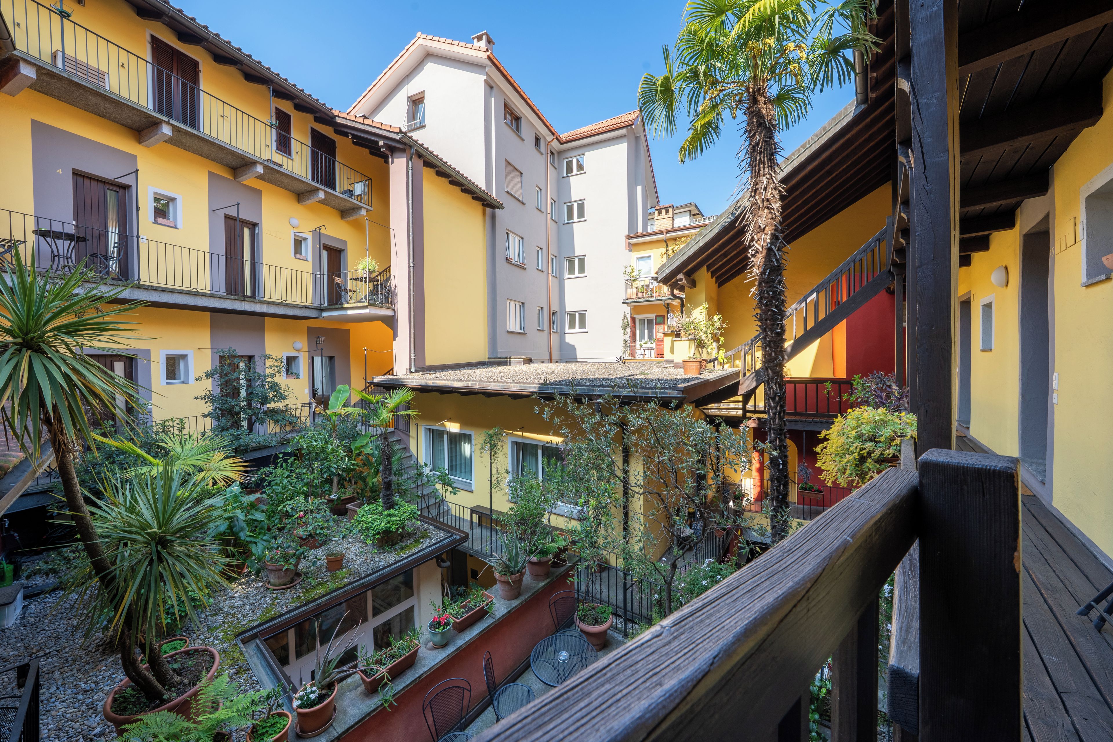A courtyard with multiple balconies, potted plants, and a wooden railing.