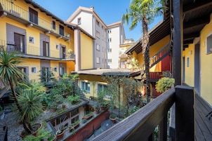 Un patio con varios balcones, plantas en macetas y una barandilla de madera.