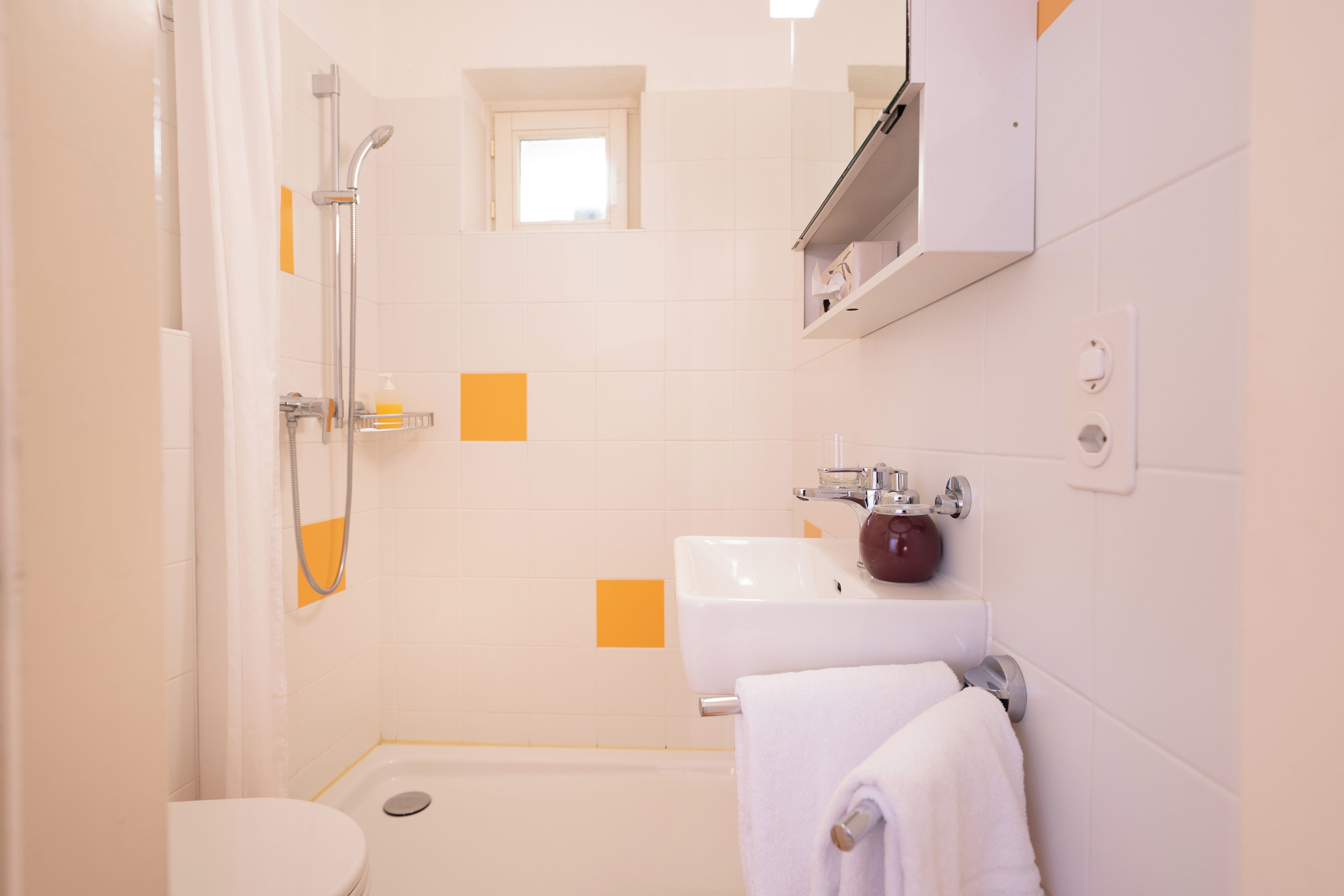 A bathroom with a shower, toilet, sink, and a towel rack.