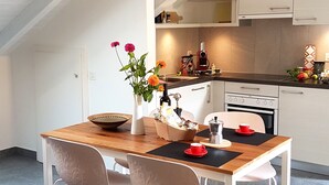 Una cocina moderna estilo loft con armarios blancos, una mesa de comedor de madera y dos sillas.
