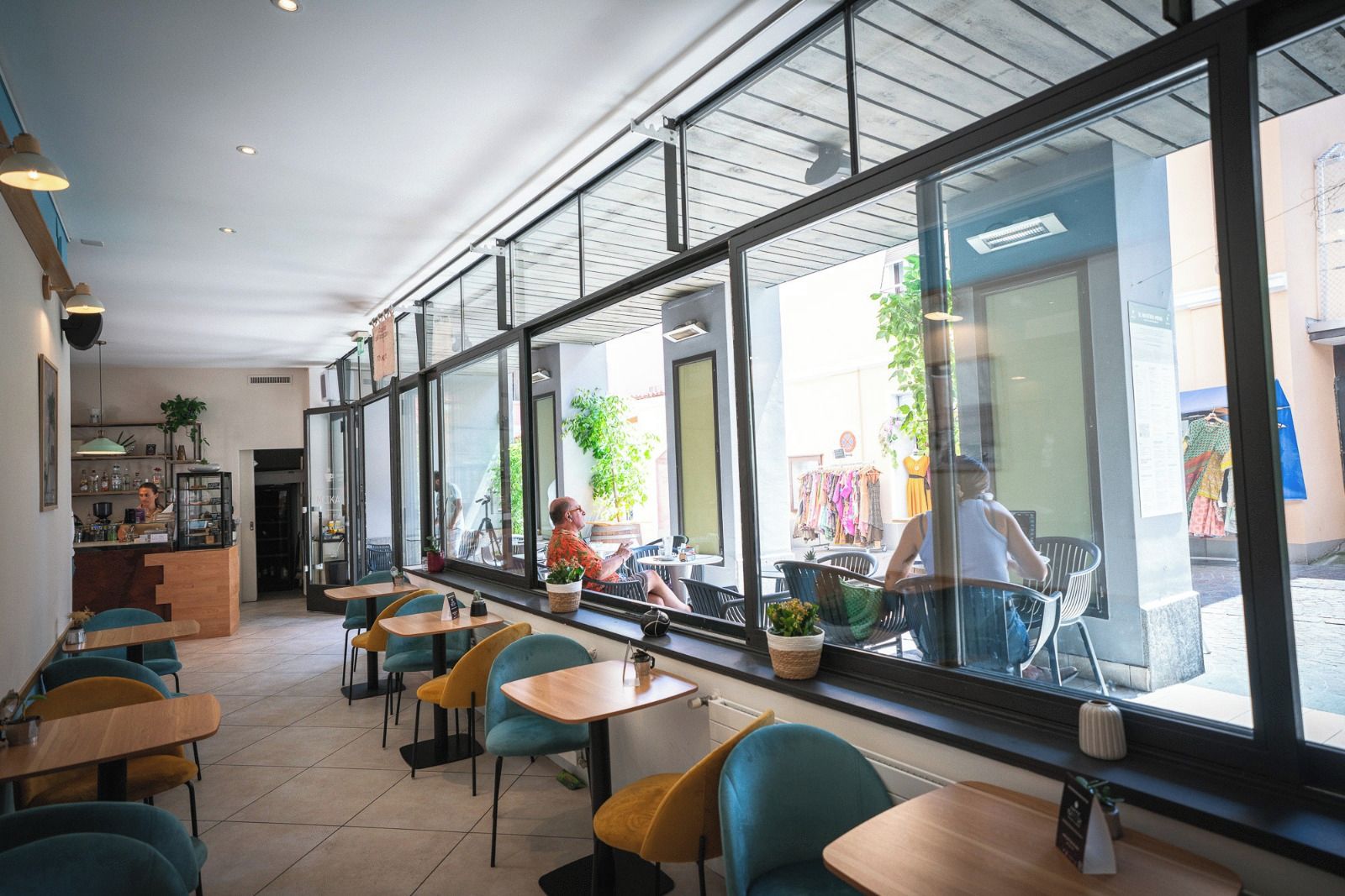 A cafe with large windows, indoor seating, and a counter area.