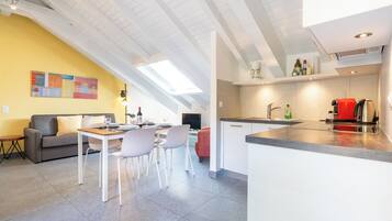 A modern kitchen with a dining area, a sofa, and a TV.