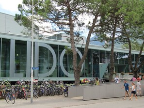 A modern building with a glass facade, a bike parking area, and a pedestrian walkway.