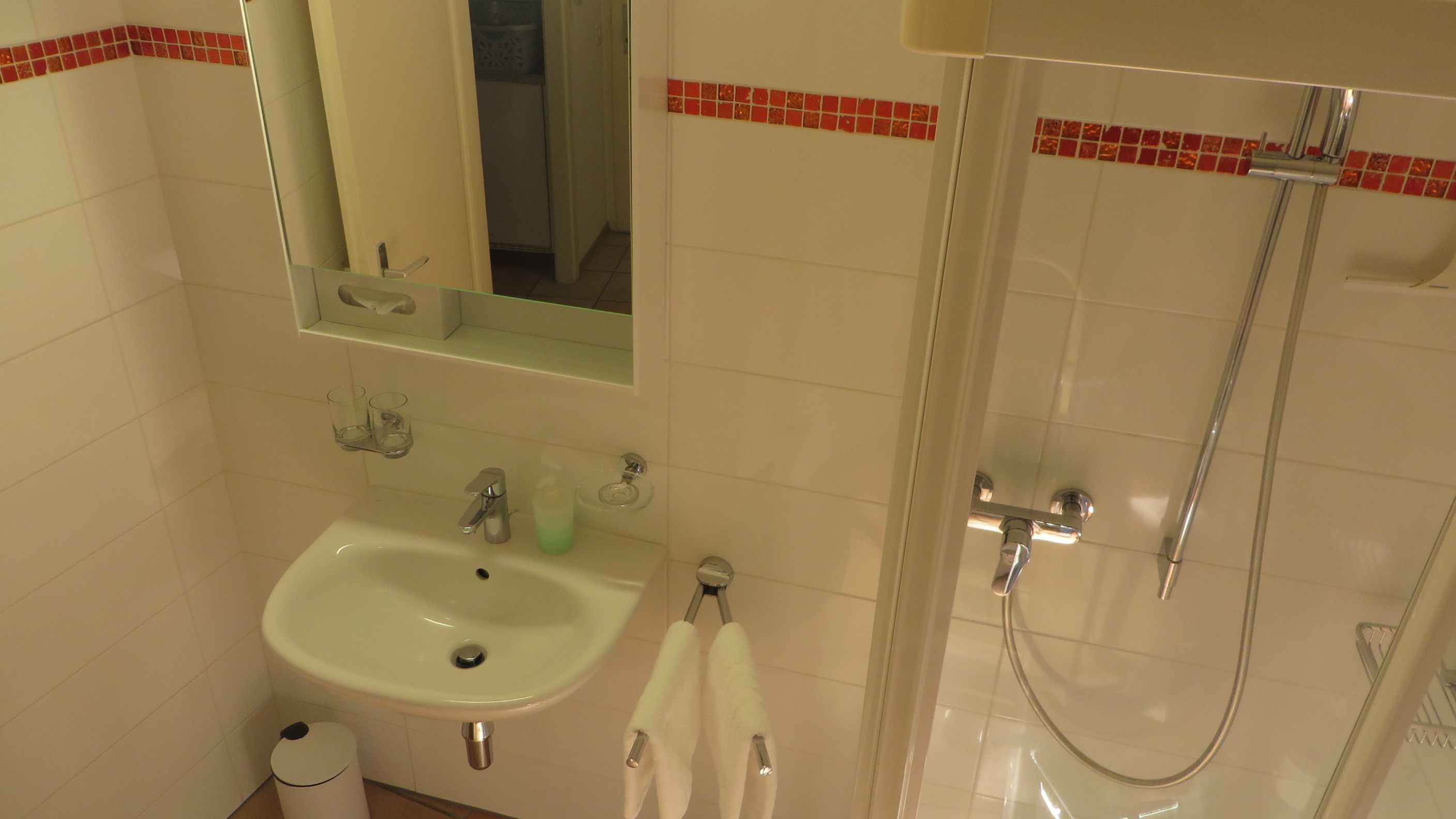 A bathroom with a sink, mirror, and shower.