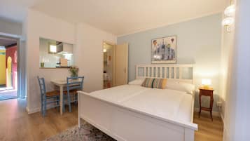Une chambre à coucher avec un lit, un bureau, des chaises, un miroir et un tableau accroché au mur.
