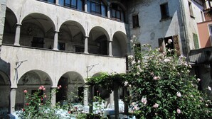 Un edificio histórico con múltiples arcos y un patio lleno de flores.