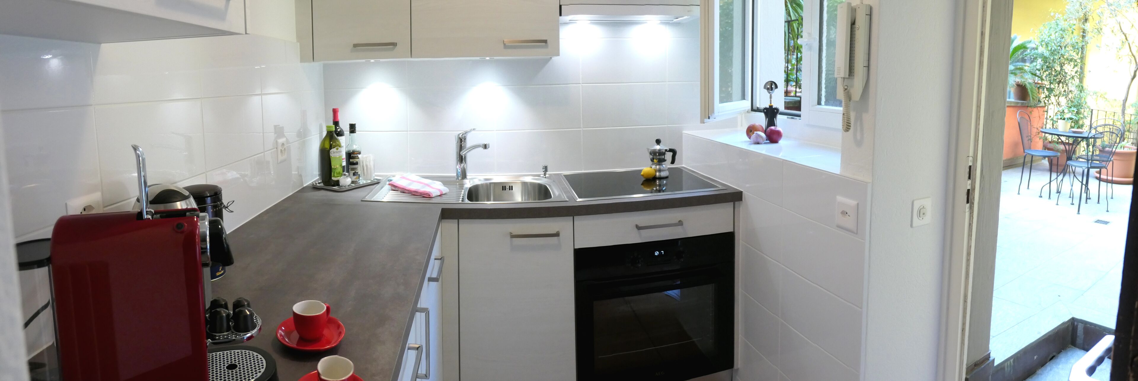 Eine moderne Küche mit weißen Schränken, einer Edelstahlspüle und einem eingebauten Backofen.