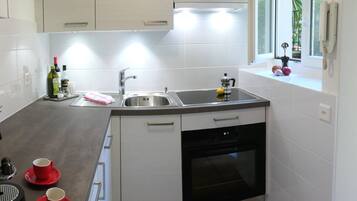 Eine moderne Küche mit weißen Schränken, einer Edelstahlspüle und einem eingebauten Backofen.