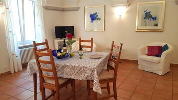A dining area with a table set for four, chairs, a television, and artwork on the walls.