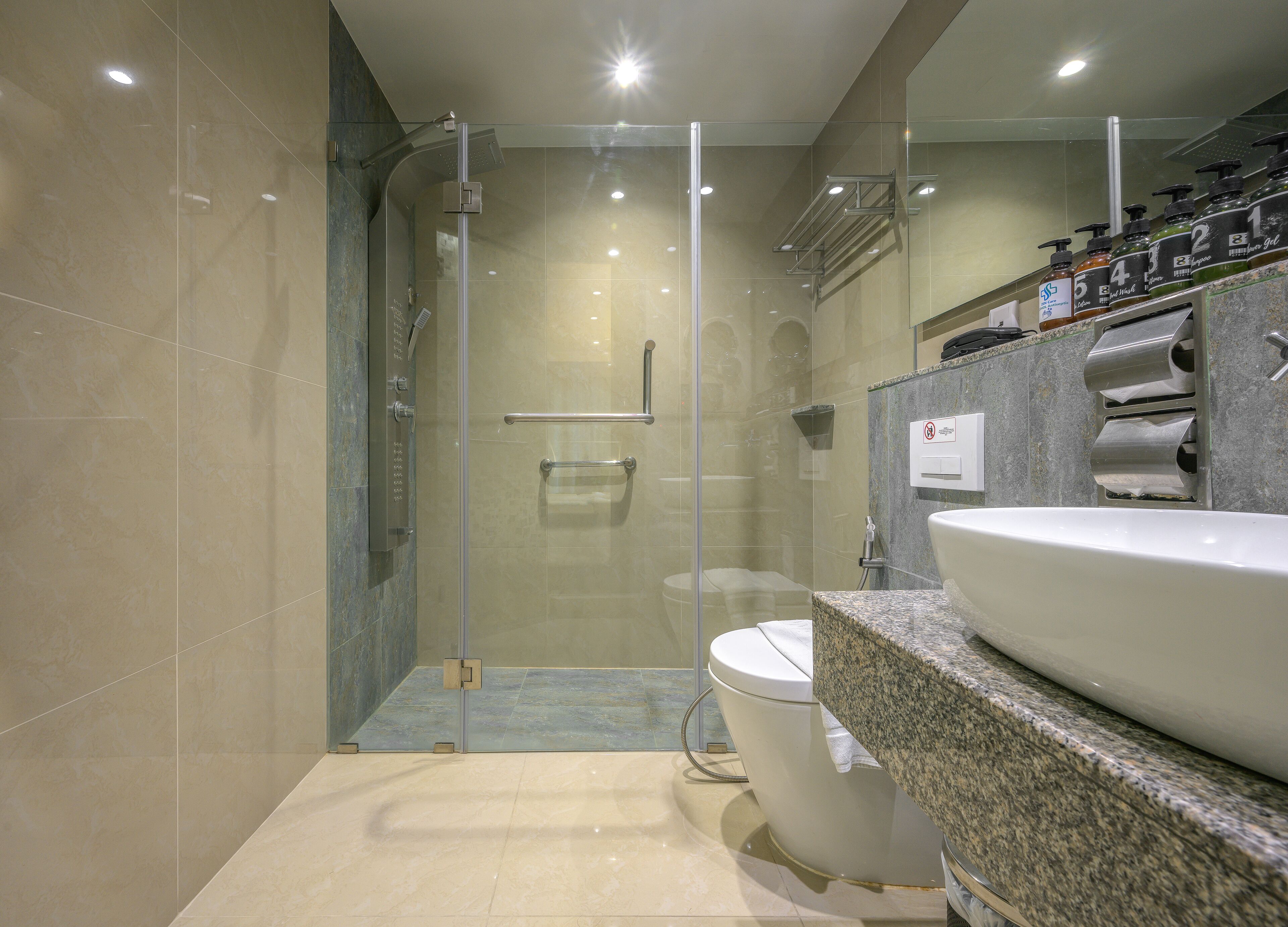 A modern bathroom with a glass-enclosed shower, a white toilet, and a granite countertop with a sink.