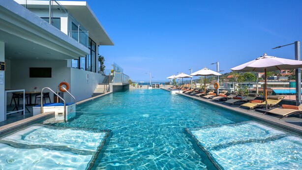 A swimming pool with lounge chairs and umbrellas, a lifeguard stand, and a clear view of the sea. - Zenseana Resort & Spa (Patong)