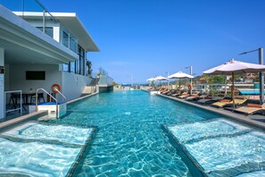 A swimming pool with lounge chairs and umbrellas, a lifeguard stand, and a clear view of the sea. - Zenseana Resort & Spa (Patong)