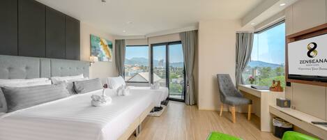 A modern hotel room with a large bed, a desk, a chair, and a TV.