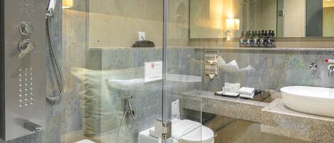 Une salle de bain moderne dotée d’une douche à parois de verre, d’une grande baignoire et d’un meuble-lavabo avec un évier et un miroir.