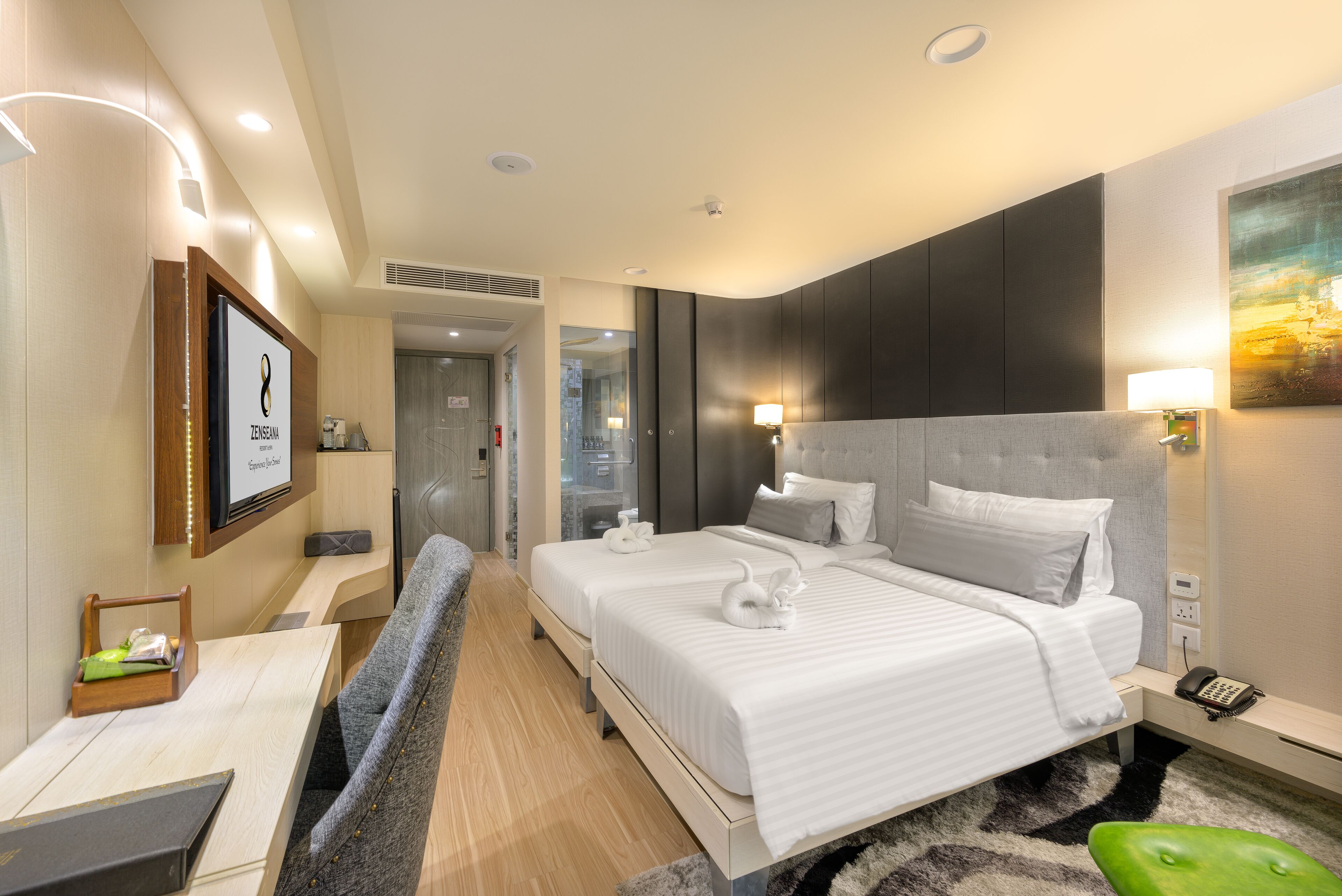 A modern hotel room with a large bed, a desk, and a seating area.