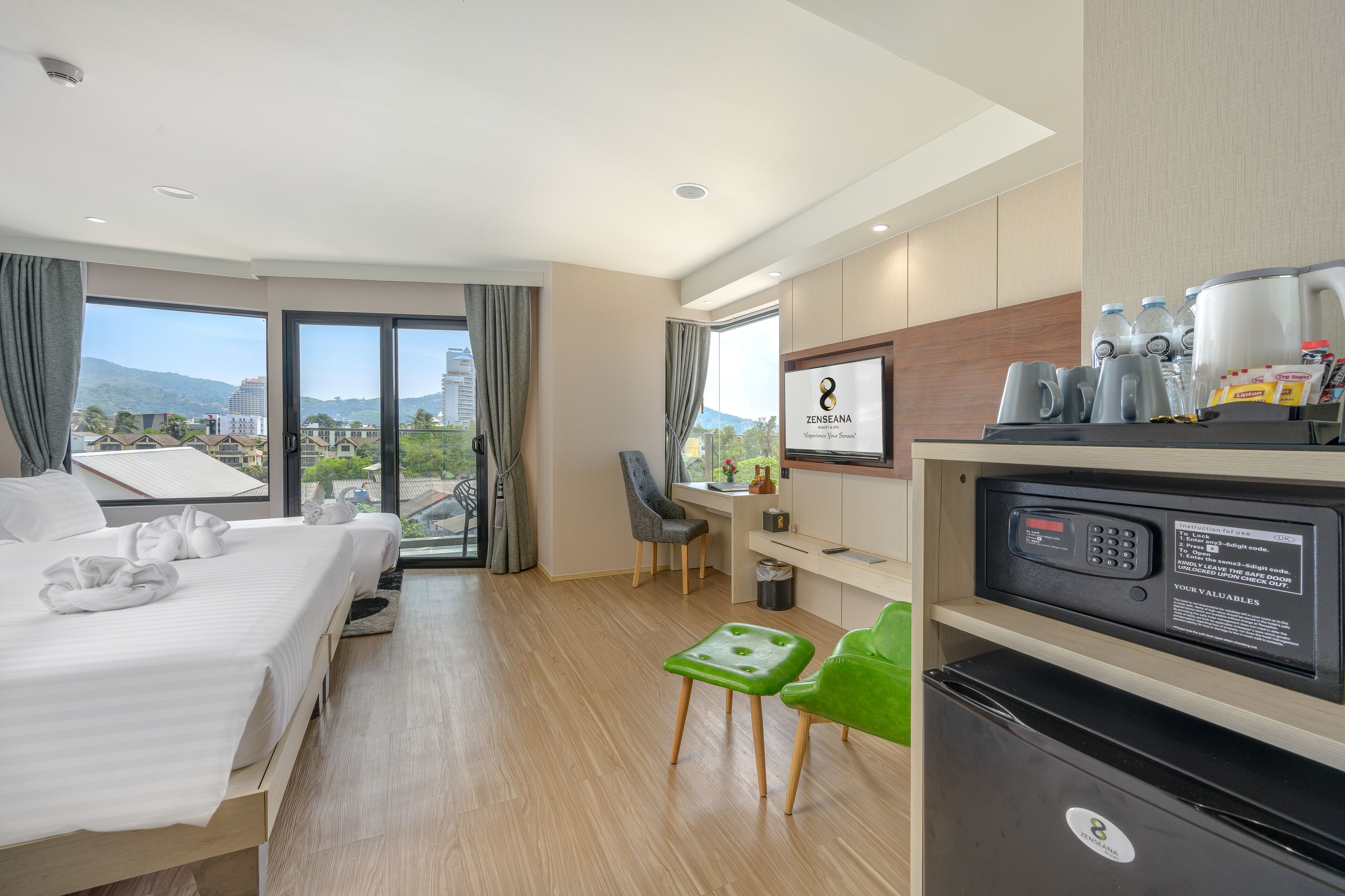 A hotel room with a bed, a desk, a chair, a refrigerator, and a view of the mountains.