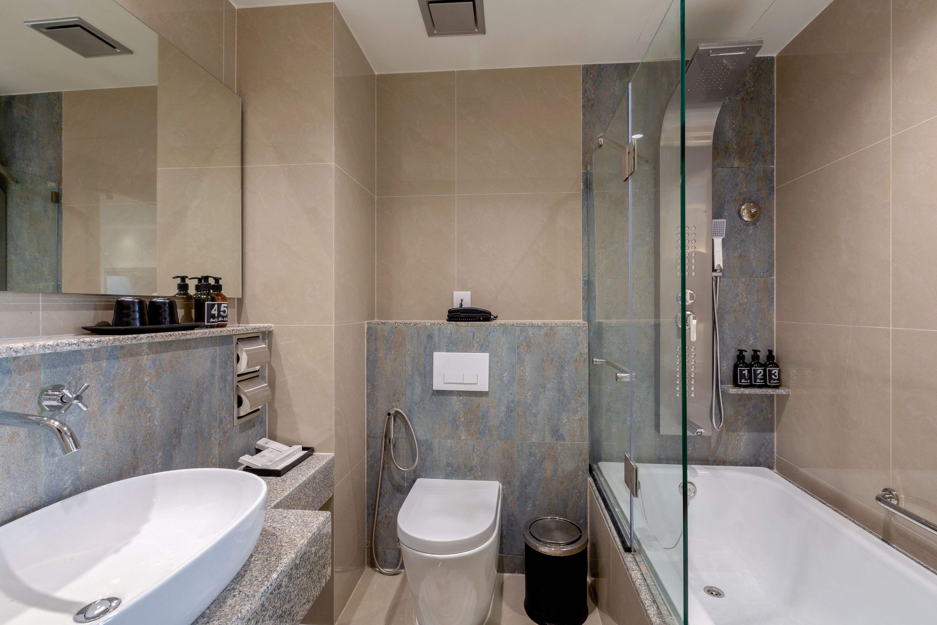 A modern bathroom with a double sink, a toilet, and a glass-enclosed shower area.