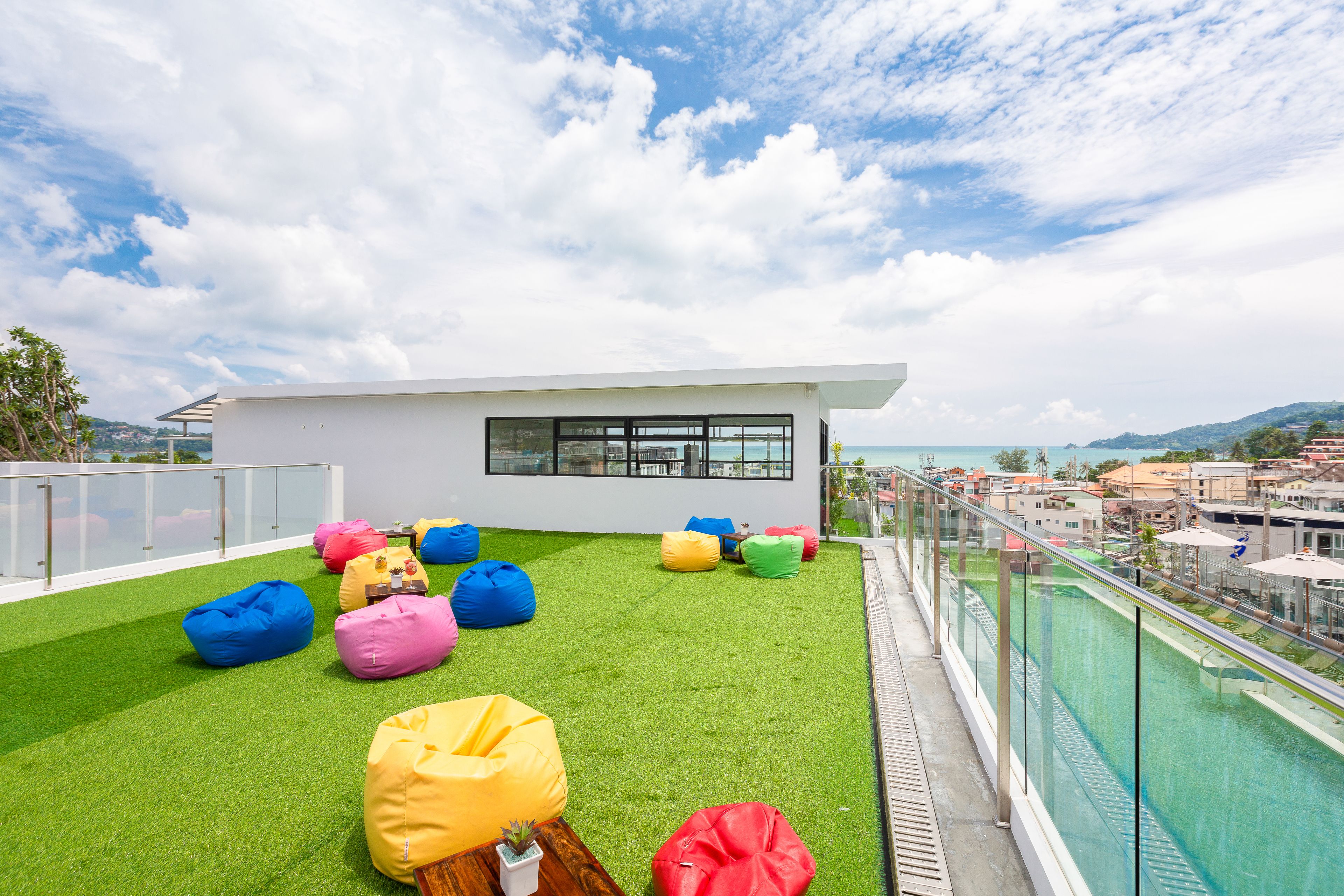 A rooftop terrace with artificial grass, colorful bean bags, and a modern building with large windows.