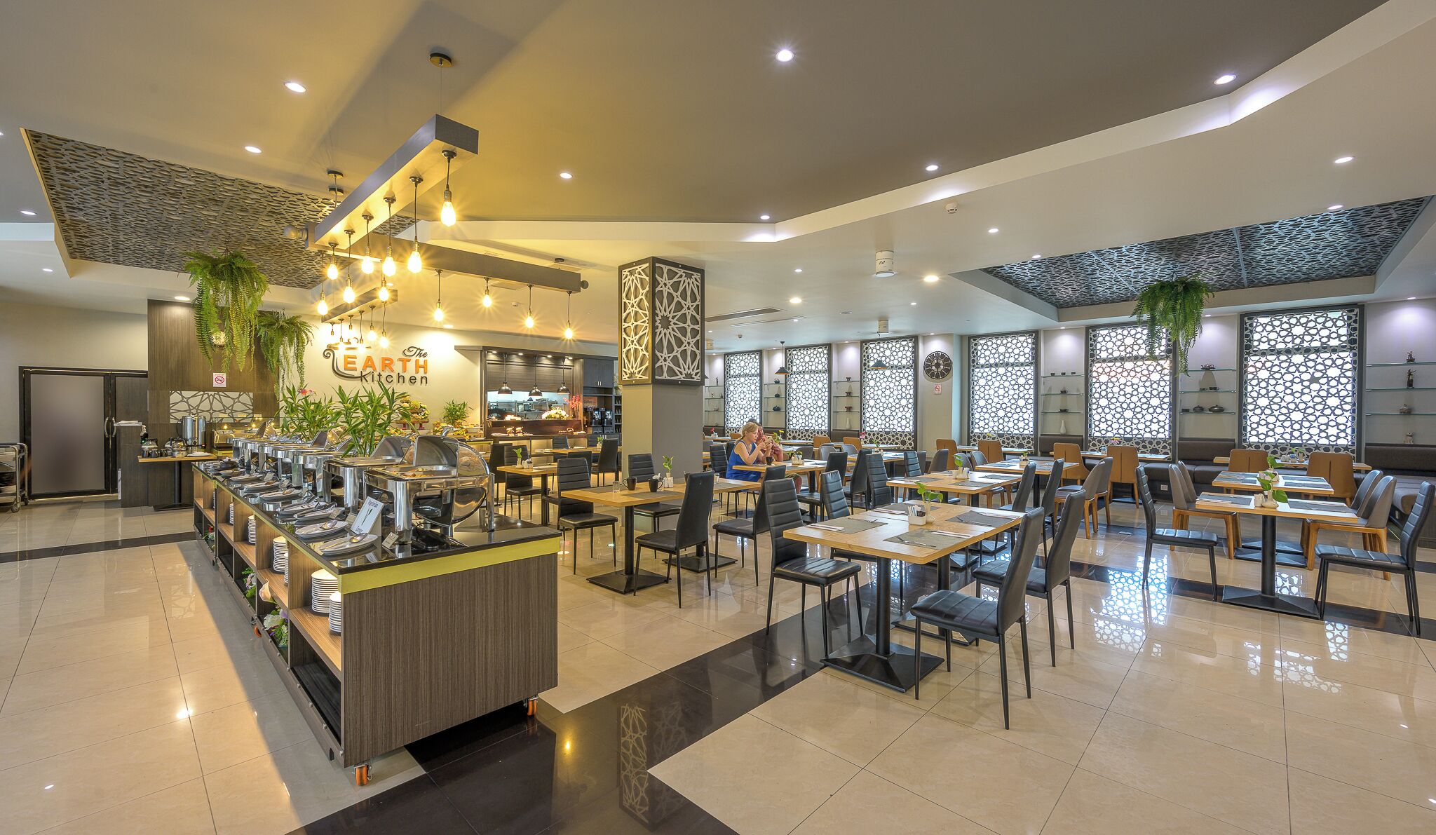 A modern restaurant with a buffet area, multiple dining tables, and a variety of seating options.