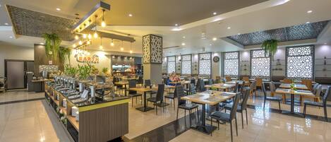 A modern restaurant with a buffet area, multiple dining tables, and a variety of seating options.