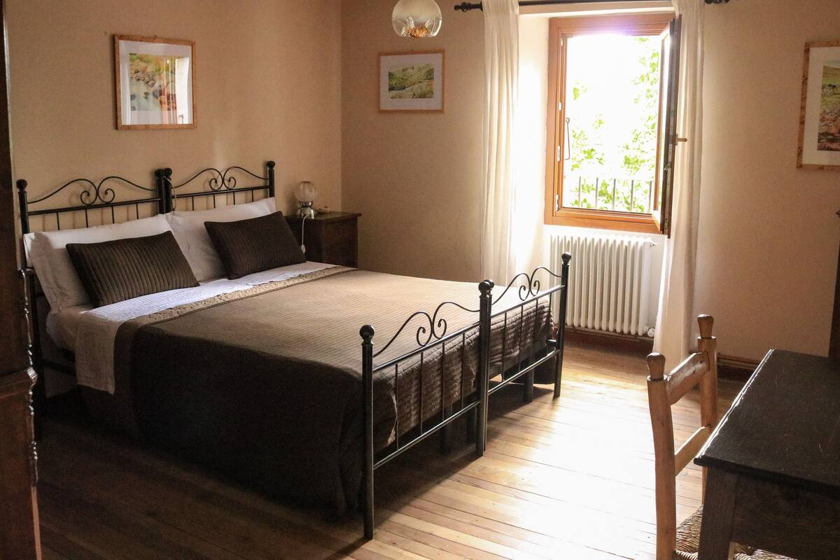 Una camera da letto con un letto, un comodino, una lampada e una finestra con tende.