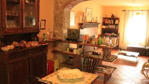 A cozy kitchen with a dining table, chairs, and a brick fireplace. - Cà Gennara B&B (Alto Reno Terme)
