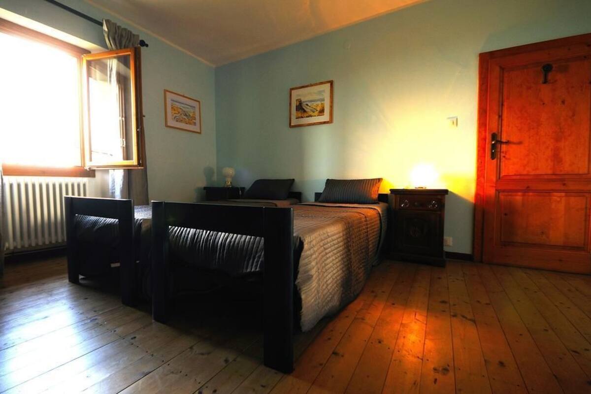Una camera da letto con un letto, due comodini, una finestra, una porta e due quadri appesi al muro.