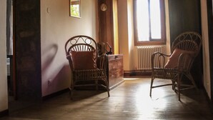 A room with wooden flooring, two wicker chairs, a small table, and a window with sunlight. - Cà Gennara B&B (Alto Reno Terme)