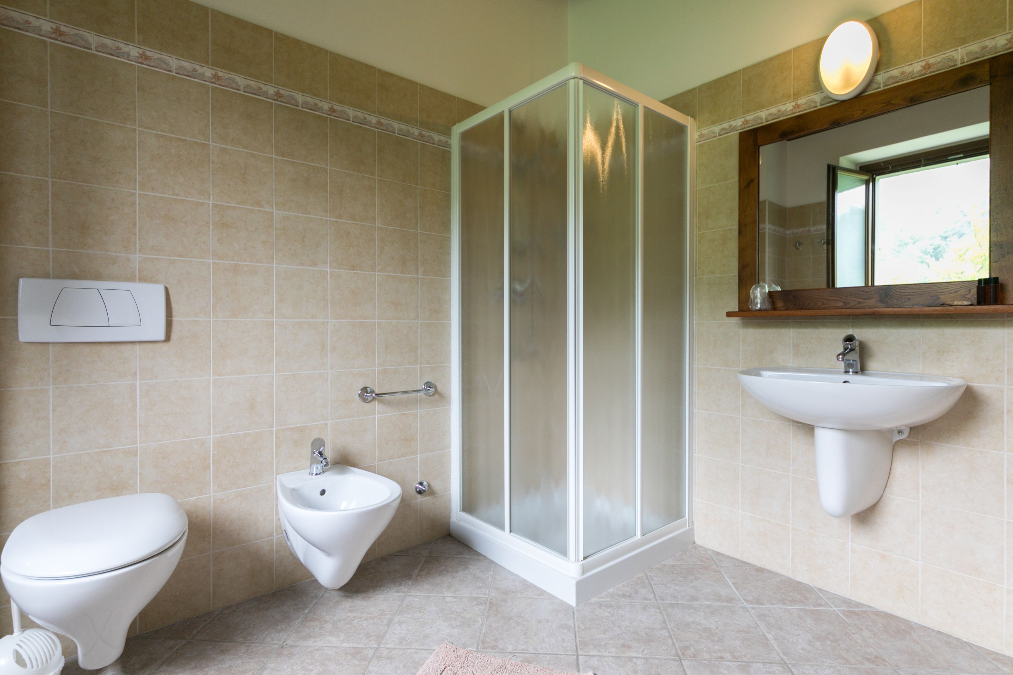 Un baño con inodoro, bidé, ducha y lavamanos.