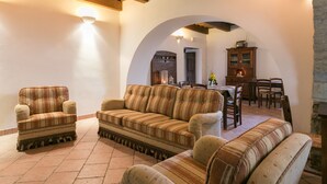 A cozy living room with striped sofas, a wooden ceiling, and a stone wall.