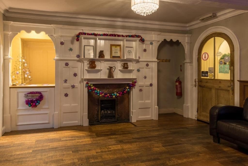 A reception area with a fireplace, a Christmas tree, and a leather couch.