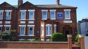A traditional red brick building with white-framed windows, a prominent entrance with an archway, and a sign indicating it is a hotel. - The Winchester (Great Yarmouth)